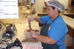 SENDING OUT GOODNESS: Robicheaux’s Specialty Candy specializes in candy making, decorating and glazed nuts. Rhonda Buckley is packaging glazed pecans to ship out to customers.  Photo by Cassandra Favre