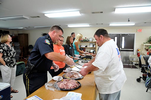 1. Come and get it: A Picayune Police officer serves food to a Pines resident during the luncheon sponsored by the police department. Photo by Ashley Collins.