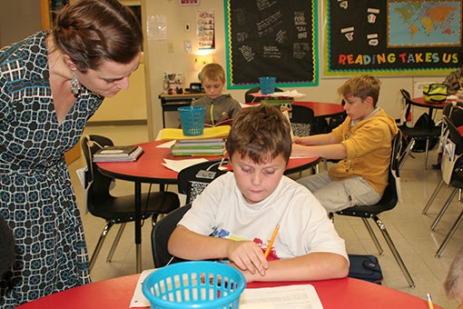PRACTICES MAKSE PERFECT: Fifth grade reading teacher Peggy Williams helps guide one of her students through an assignment during class time. Photo by Ashley Collins.