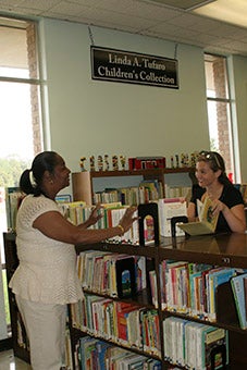 CONVERSATION OVER BOOKS: Crosby library employees Missy Ellis pictured on left and Sarah Hirstius talk to one another as they stock bookshelves in the children’s section of the library. Photo by Ashley Collins. 