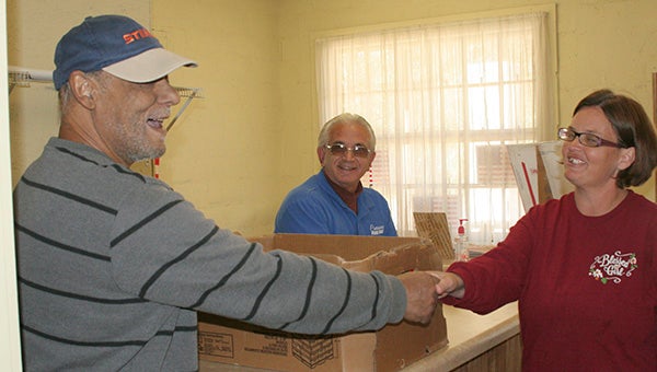a helping hand: From left, Crossroads Food Pantry volunteers Terry Duplessis and Johnny Scalise deliver food to client Jennifer Bennett.  Photo by Cassandra Favre