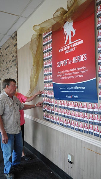 SUPPORTING VETERANS: From left, Bobby and Randy Graves of Poplarville hang their dedication cards on the Wall of Honor at the Winn-Dixie in Picayune, located at 1701 Highway 43 North.  Photo by Cassandra Favre 