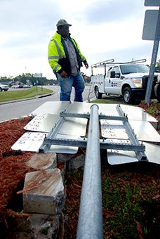 a bad sign: MDOT worker John Merritt surveys damage done to highway signs at the intersection of Highway 11 and Highway 43 North on Tuesday. Monday morning, a vehicle crashed into the signs and planter. 