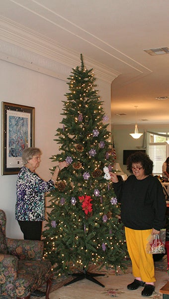 SPREADING CHEER: From left, Kathleen Penton and Gladys Cruz decorate the snowflake Christmas tree at the Senior Center.  Photo by Cassandra Favre 