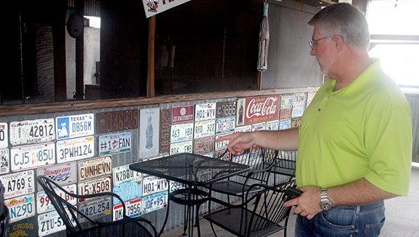 NATIONWIDE DECOR: Stonewall’s BBQ founder Tony Smith shows off the many license plates sent to him by loyal customers.  Photo by Jeremy Pittari