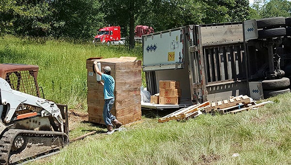 A crew works on unloading the contents of a flipped trailer into another truck on the northbound bank of Interstate-59.