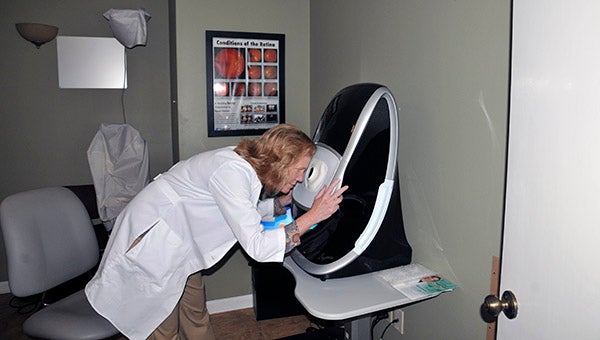 INNOVATIONS: Dr. Lori Blackmer, owner of Picayune Eye Clinic, peers into Optos, a machine that allows for a 220 degree view of the back of the eye. With the use of this machine, dilation of the eyes, is in most cases, unnecessary.  Photo by Cassandra Favre  