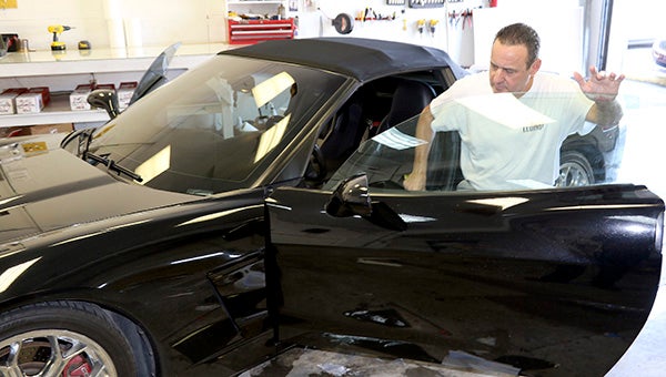 COOL RIDE: Fred Davis works to tint the windows on this Corvette at his Picayune business, which also offers professional carpet cleaning services. Photo by Jeremy Pittari