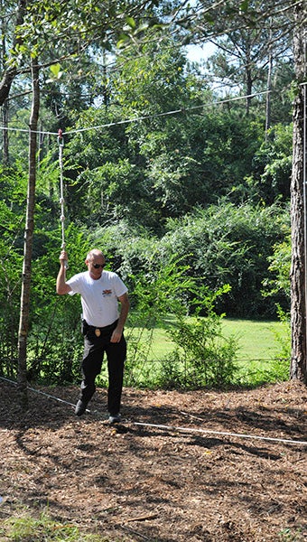 ROPES COURSE: Pearl River Community College Chief of Police Doug Rowell demonstrates one of the team building activities on the ropes course during the opening of the Wildcat Wellness Ropes and Obstacle Course Friday.  Photo by Cassandra Favre  