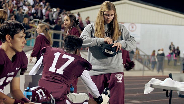 Brooke Walker looks into her medical kit to finish taping  V.J. Holt’s (17) ankle during a Picayune varsity football game. Photo by Taylor Welsh.