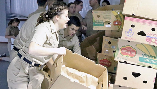 working together: Dozens of Pearl River Central High School NJROTC participants assisted volunteers at Manna Ministries with preparing food deliveries on Tuesday.  At top, NJROTC participants organize boxes in preparation for food to be placed inside. Directly above, Manna Ministries volunteers get plastic bags ready before the delivery truck full of food arrives.  Photo by Jeremy Pittari