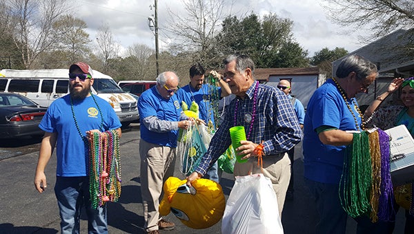 Rotarians gather outside Bridgeway with Mardi Gras beads and other gifts to throw in celebration of the holiday. Photo by Linda Gilmore