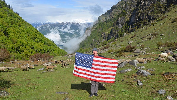 Bradley Booth holds up an American flag while hiking in the Himalayas in Manali. 